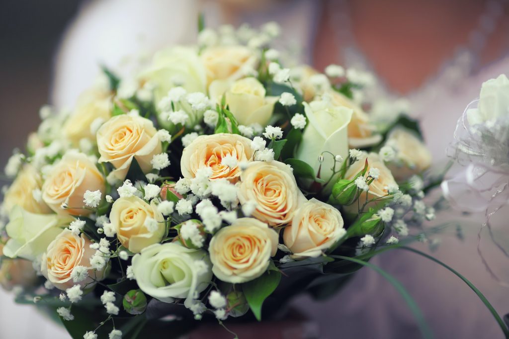 Round bouquet of small roses in hands of bride